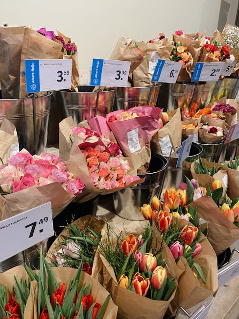 A display of various floral bouquets arranged in metal buckets and wrapped in brown paper at Upminster Florist, featuring a range of flowers including pink roses, peach and pink spray roses, vibrant o